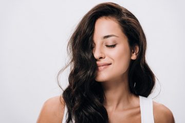 Smiling brunette beautiful woman with closed eyes and long healthy and shiny hair