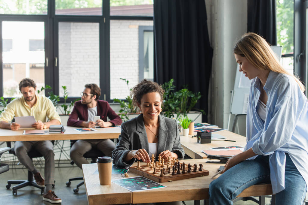 african american businesswoman playing chess with colleague in office